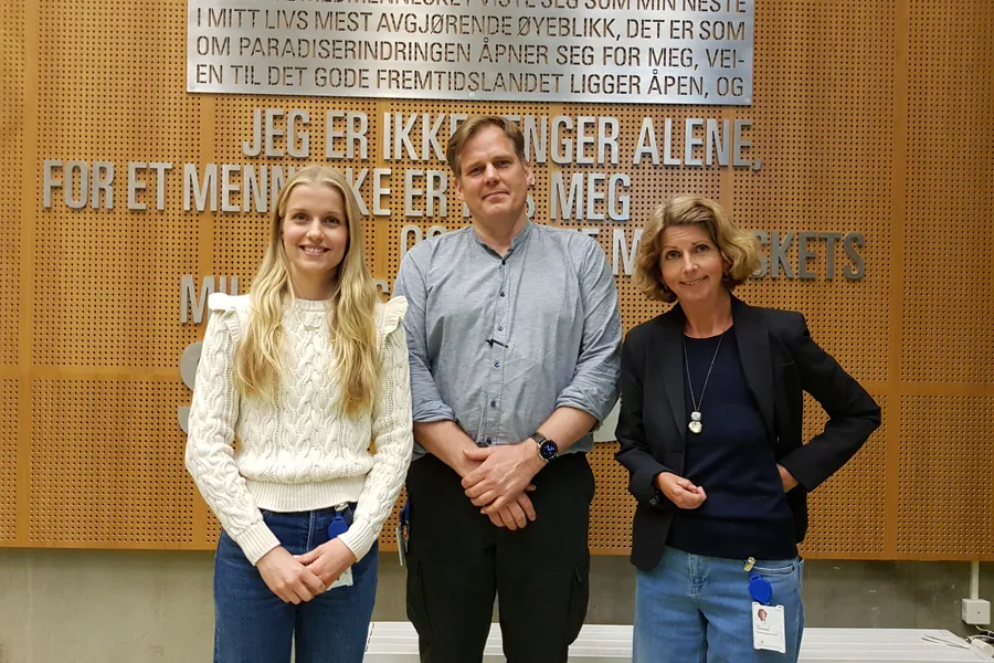 De tre foreleserne smiler står foran en vegg og smiler til fotografen