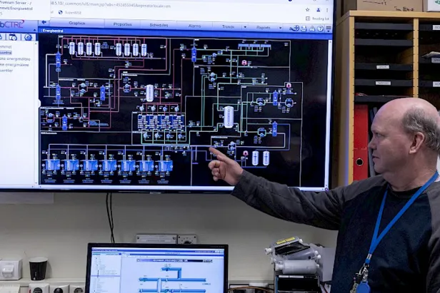 Foto av mann som peker på skjerm som viser oversikt over energisentralen