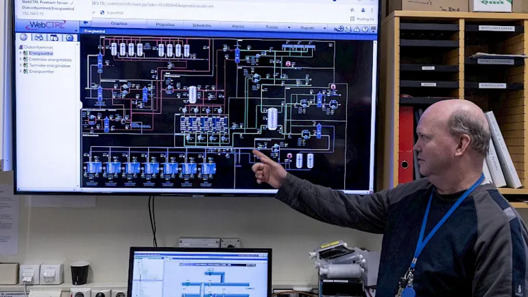 Foto av mann som peker på skjerm som viser oversikt over energisentralen
