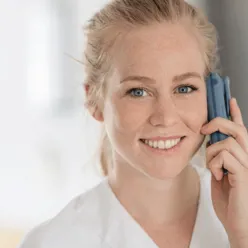 Kvinnelig sykepleier smiler mens hun snakker i telefon