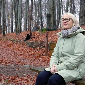 Dame som sitter på en benk i skogen