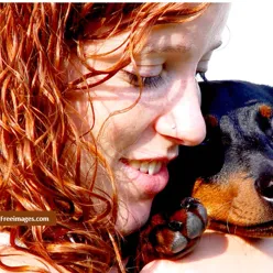 Jente med rødt hår holder en hund opp til kinnet