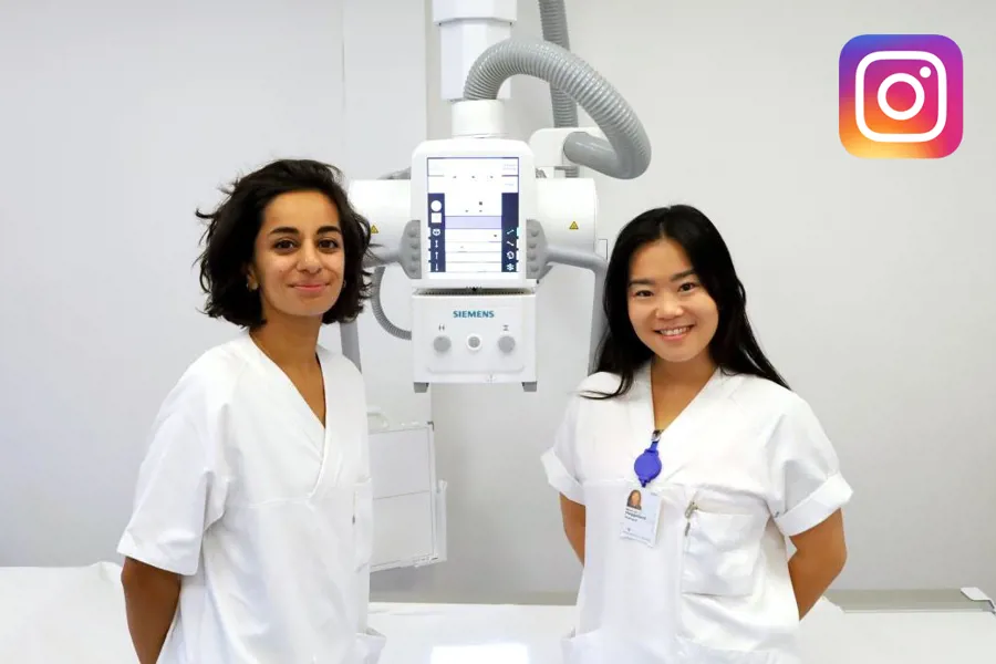 To smilende radiologer poserer foran røntgenapparat