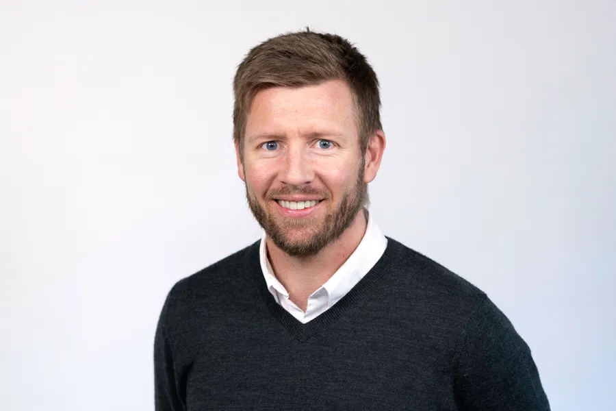 Mann ser inn i kamera og smiler