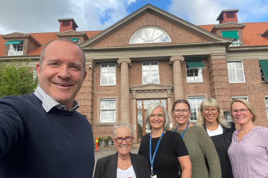 En gruppe mennesker som poserer for et bilde foran en bygning