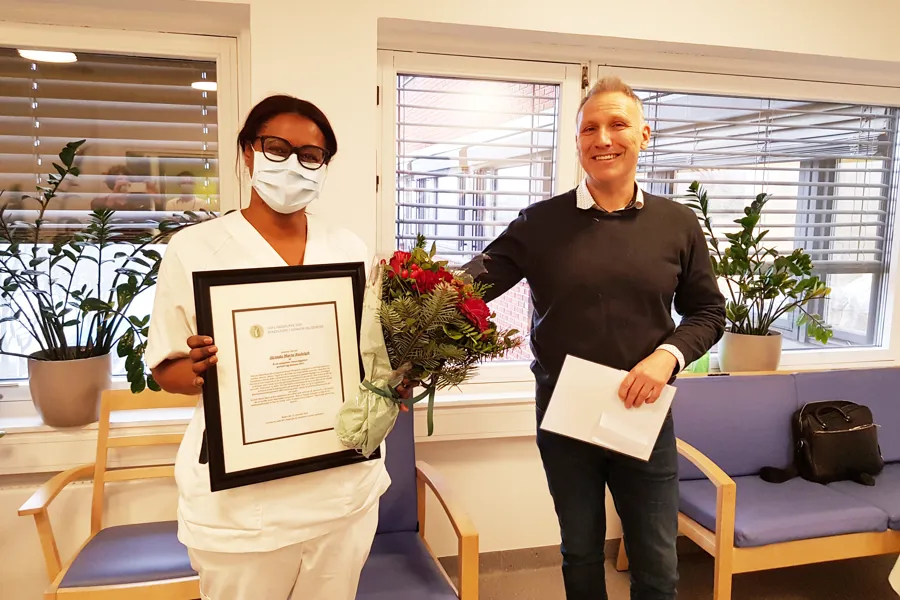 Alcinda Maria Rudolph med blomster, diplom og gavesjekk ved siden av Tor Engevik